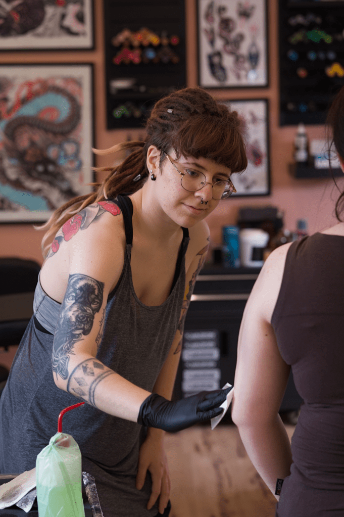 Noora wiping a client's arm after a tattooing session